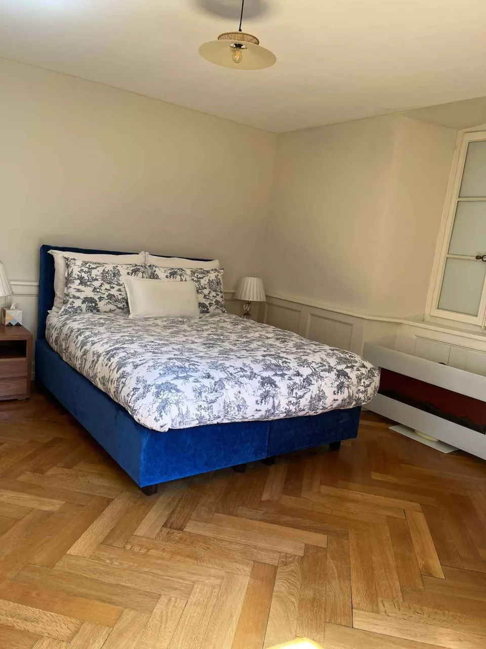 Gemütliches Schlafzimmer mit blauem Bett und Fischgrätparkett