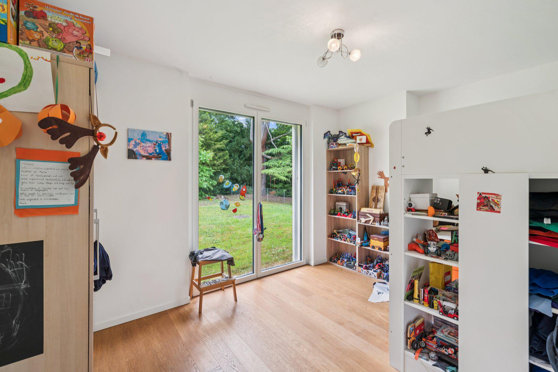 Hell eingerichtetes Kinderzimmer mit Gartenblick