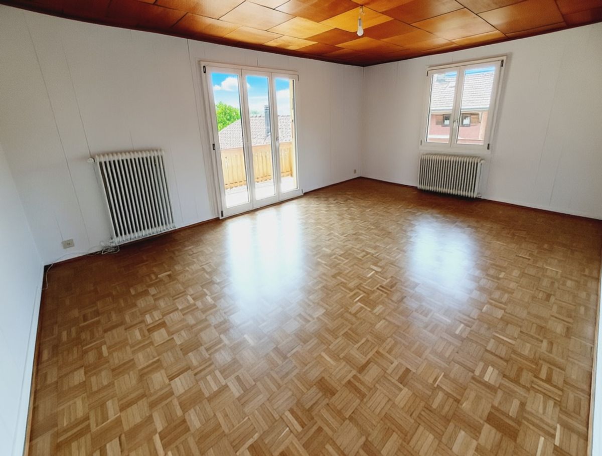 Leerer Wohnraum mit Balkon und Parkettboden