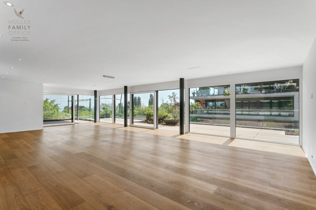 Heller, leerer Wohnraum mit großen Fensterfronten
