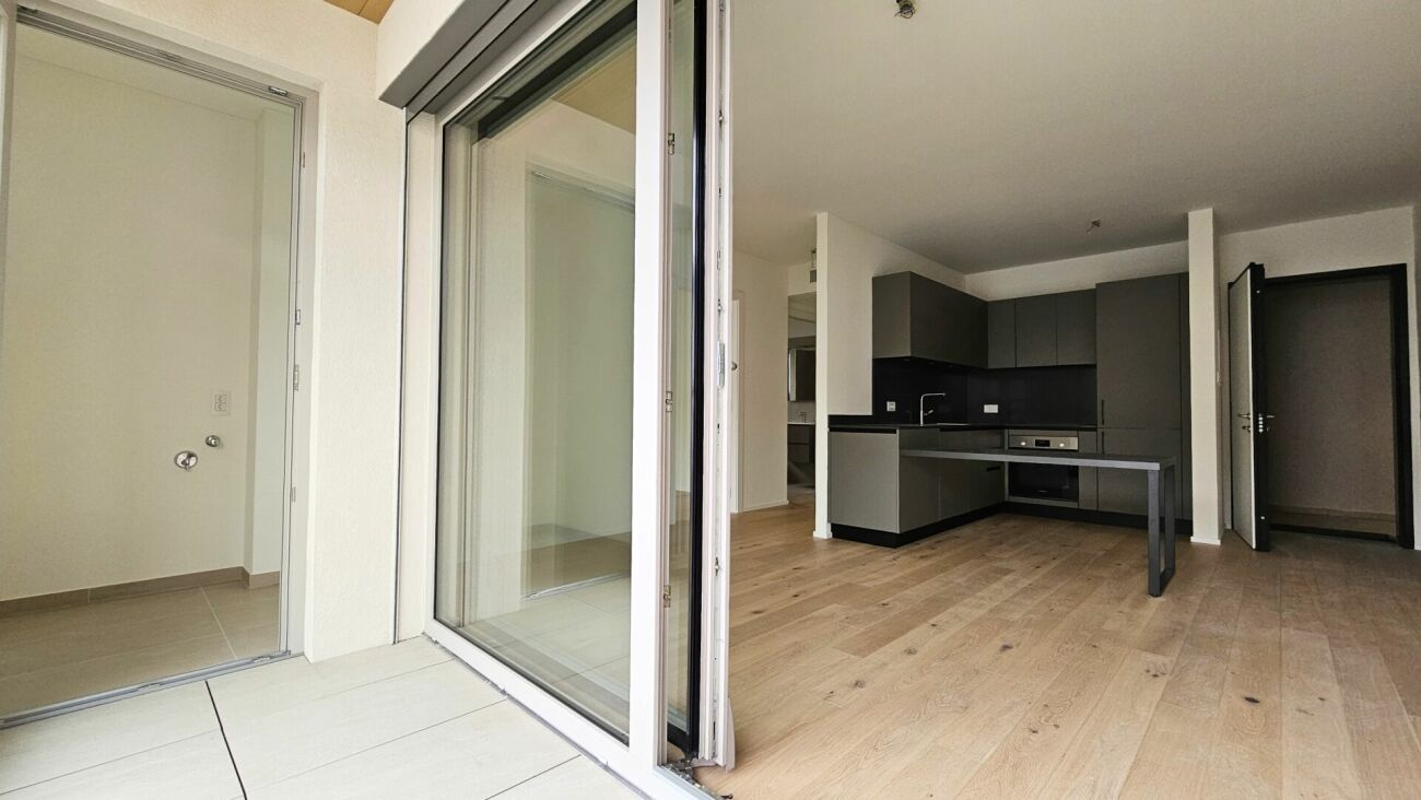 Offener Wohnbereich mit Küche und Zugang zum Balkon