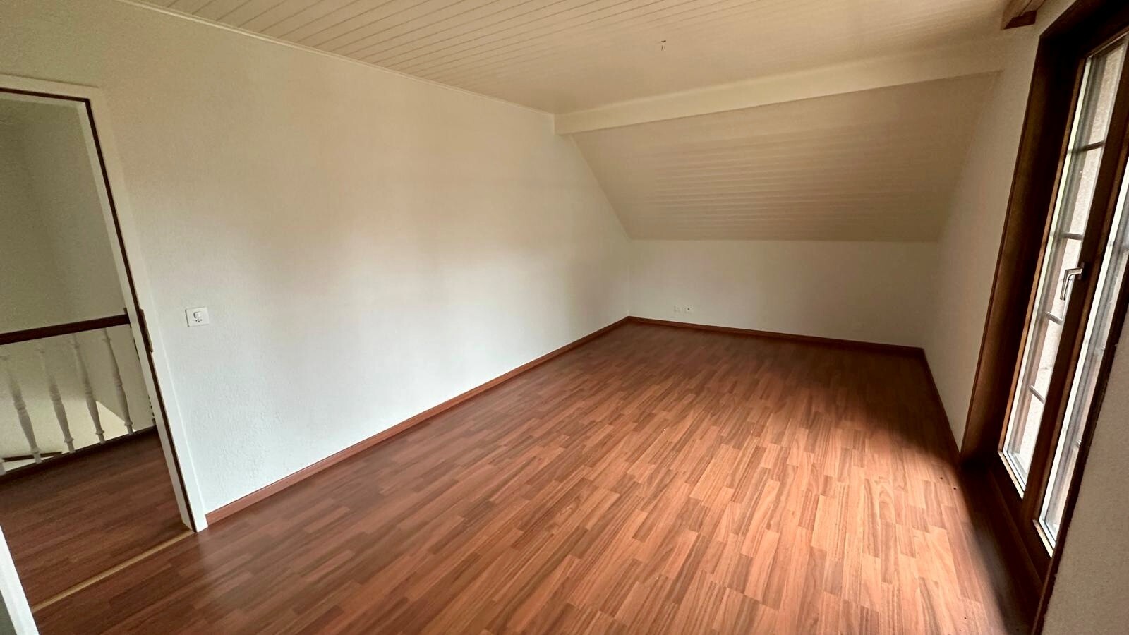 Leerer Dachgeschossraum mit Holzoptik-Boden