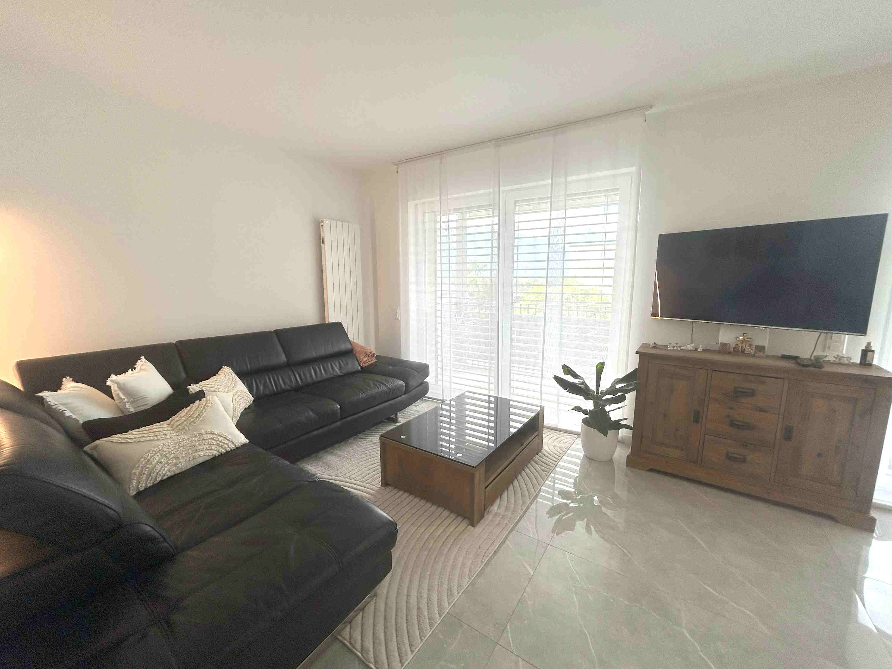 Helles Wohnzimmer mit schwarzer Eckcouch und TV