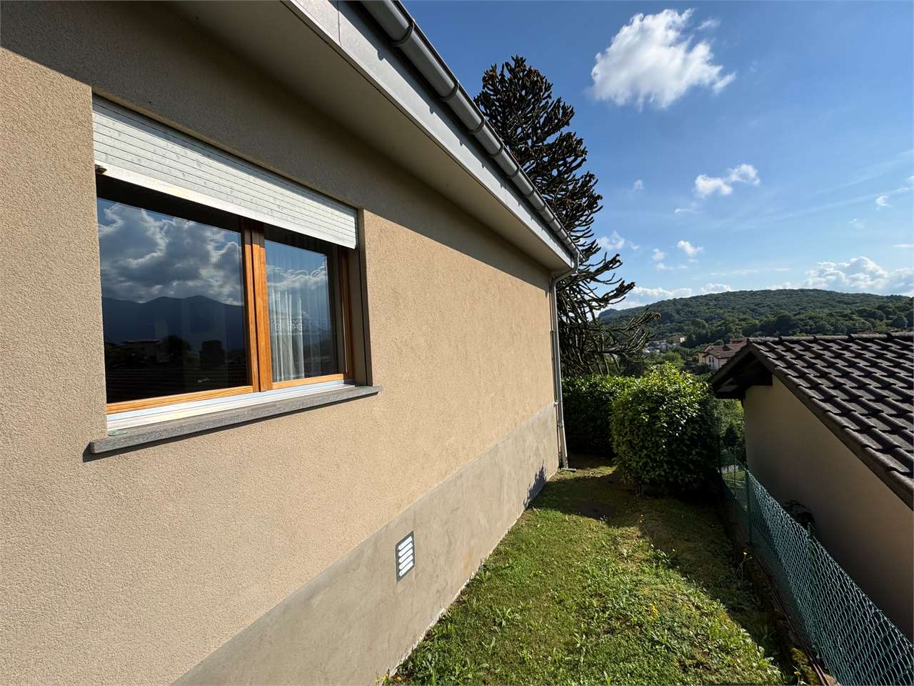 Hausaußenansicht mit Gartenhang und Blick ins Tal