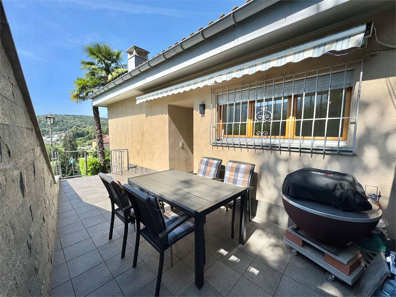 Überdachte Terrasse mit Esstisch und Grill