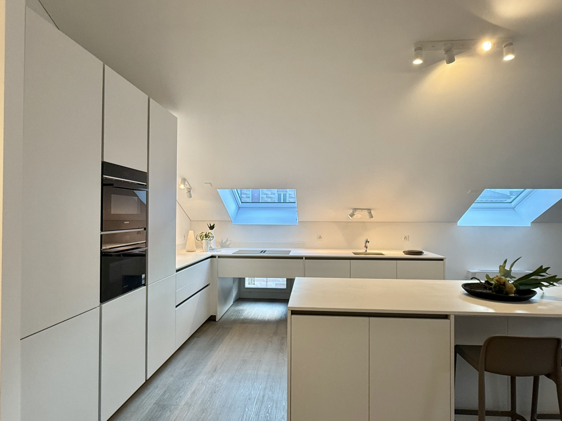 Moderne weiße Dachgeschossküche mit Insel