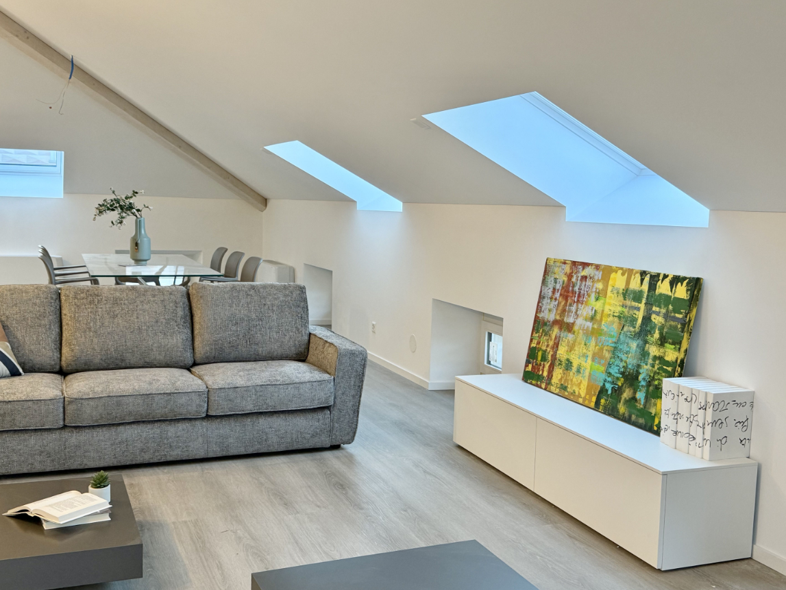 Heller Dachgeschoss-Wohnraum mit Sofa und Velux-Fenstern
