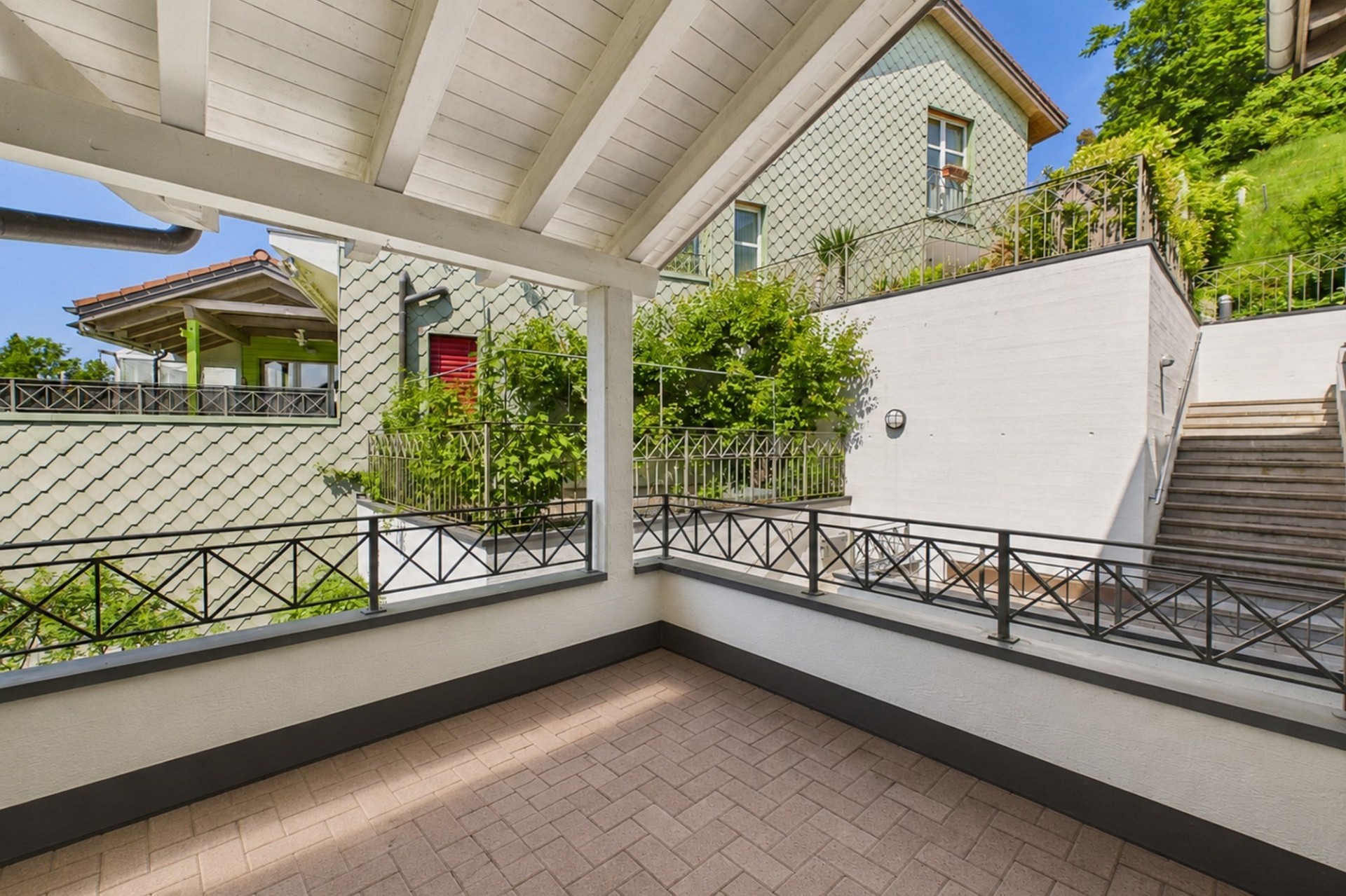 Überdachter Balkon mit Blick auf Nachbarhäuser und Hanglage