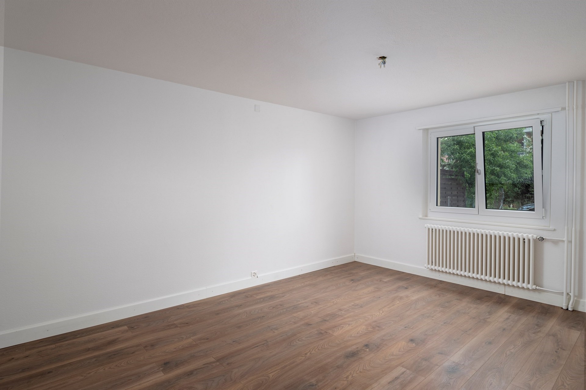 Leerer heller Raum mit Fenster und Heizkörper