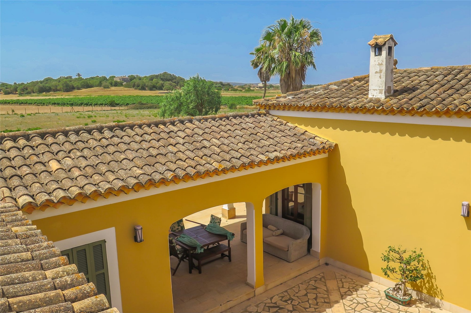 Mediterraner Innenhof mit gelber Fassade und Terrakottadach