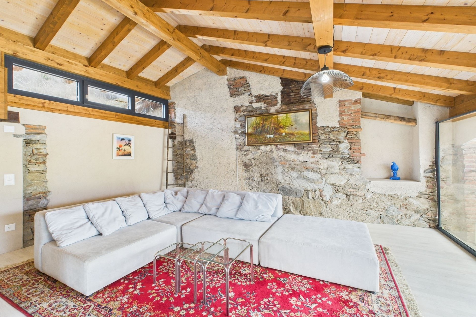 Gemütliches Wohnzimmer mit rustikalen Holzbalken und Natursteinwand