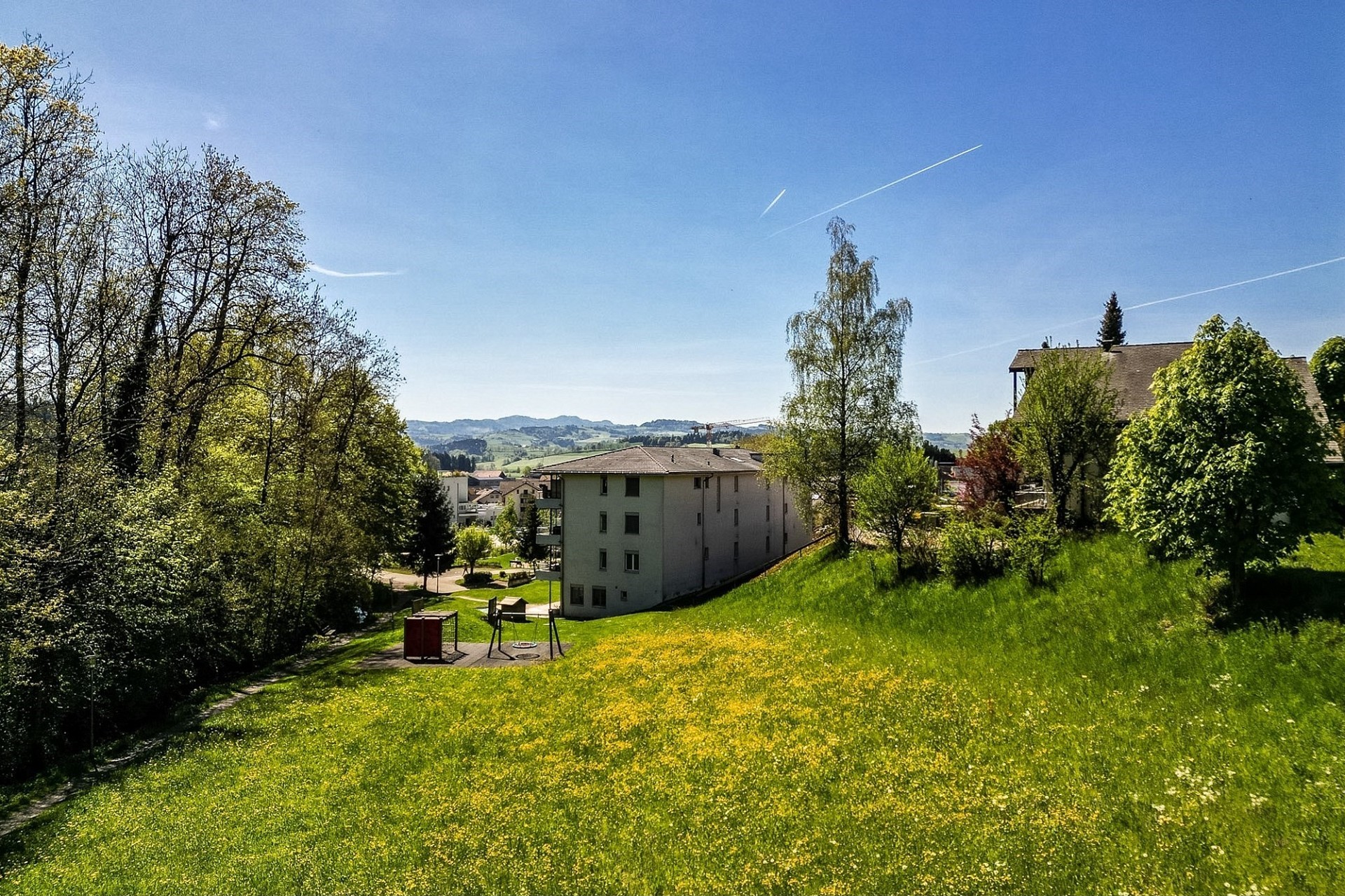 Grüne Hanglage mit Wohngebäuden und Weitblick