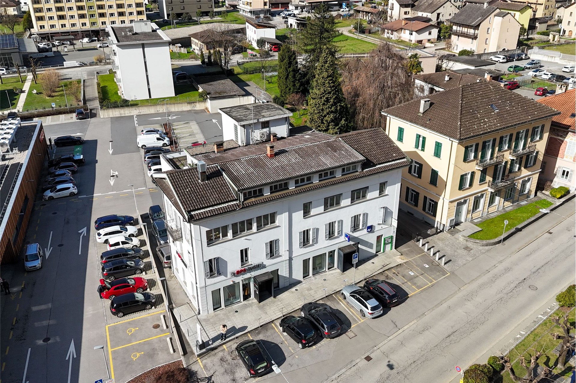 Luftaufnahme eines Wohn- und Geschäftshauses an einer Straße mit Parkplätzen