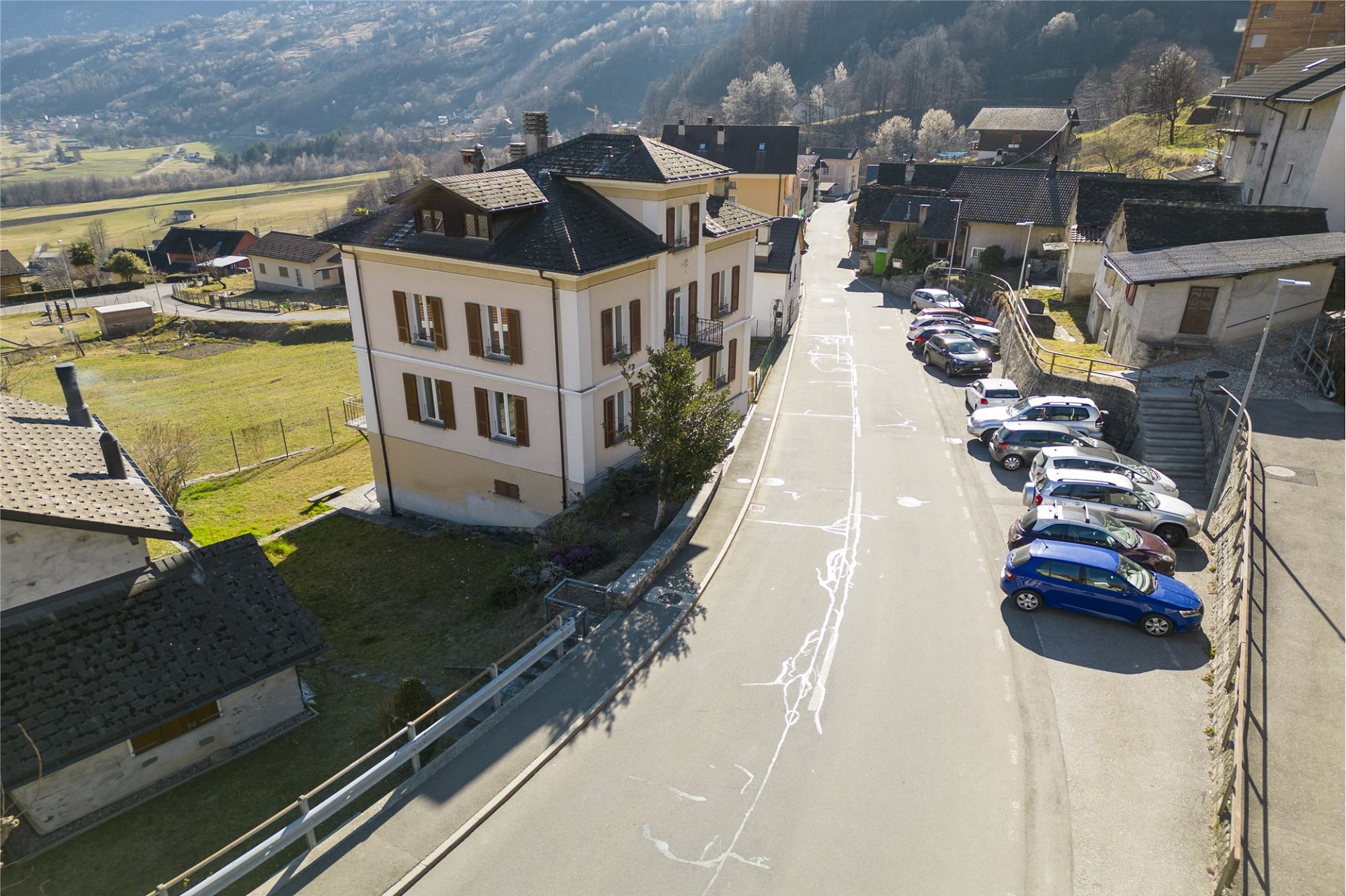 Dorfstraße mit Mehrfamilienhaus und Bergblick