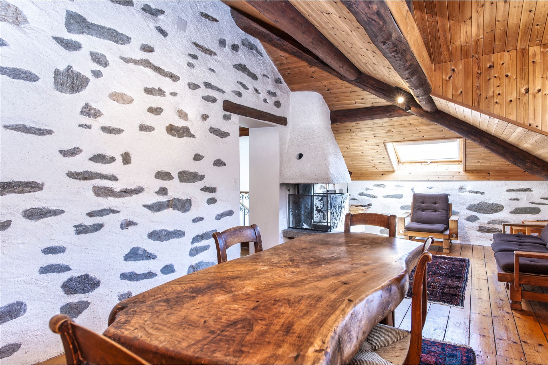 Gemütlicher Dachgeschossraum mit Holzbalken und Natursteinwand
