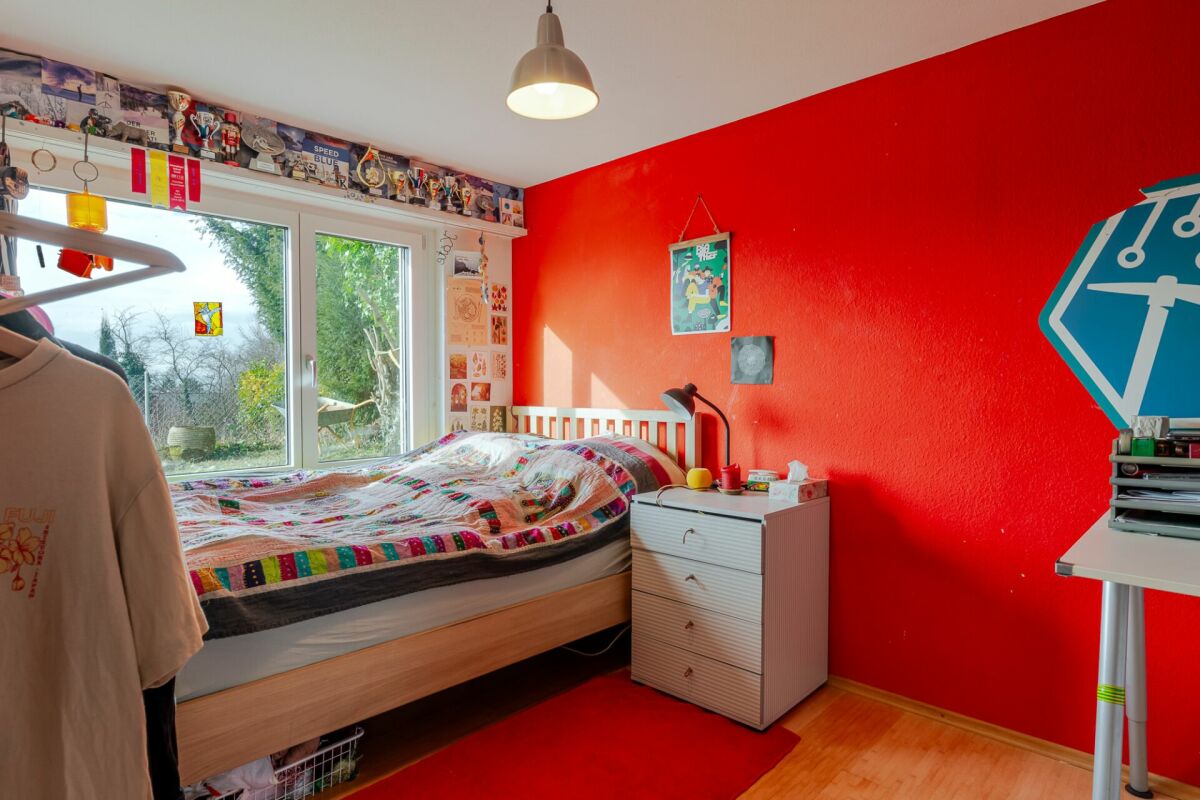 Buntes Kinderzimmer mit Bett und roter Akzentwand
