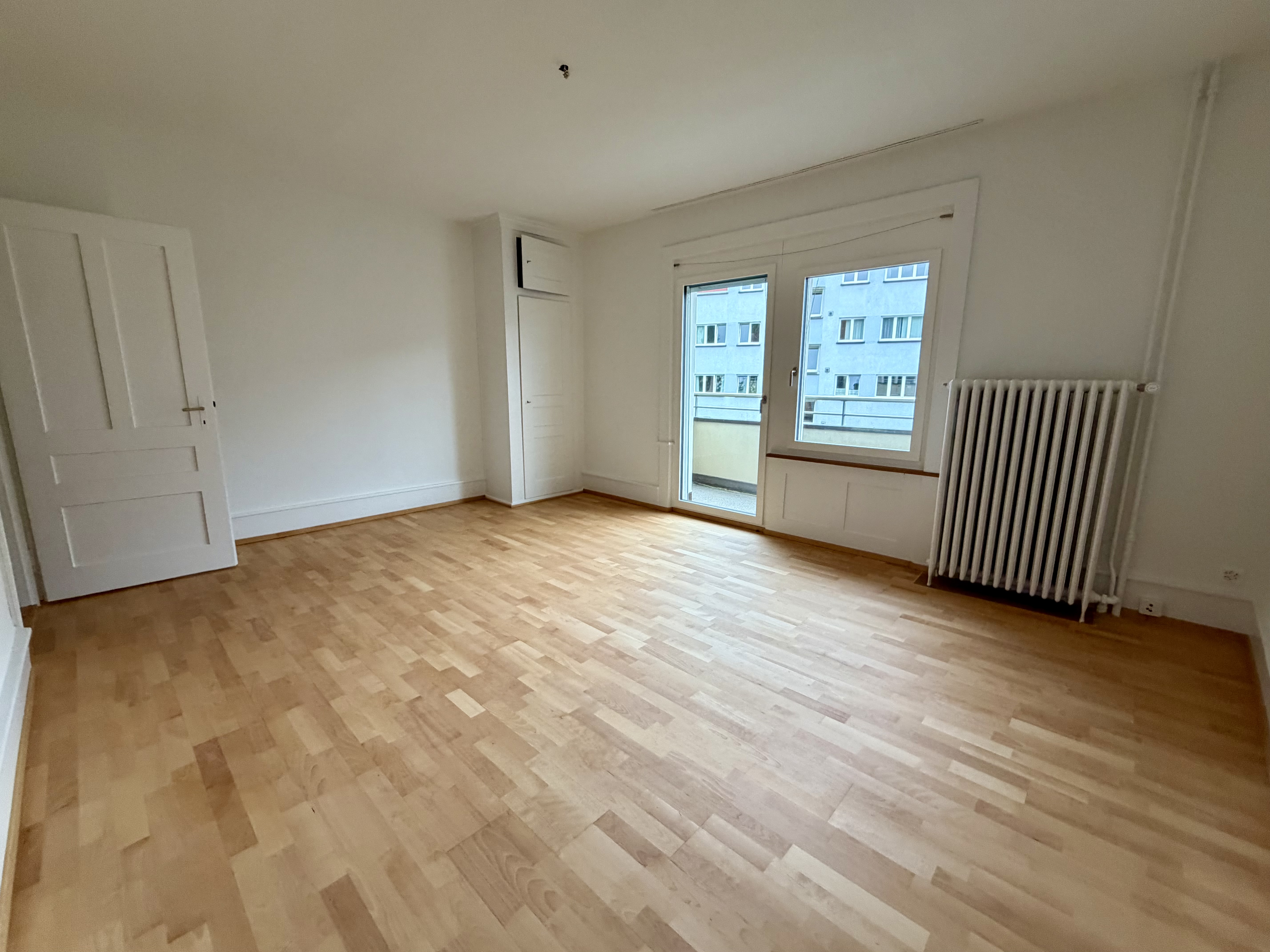 Heller leerer Wohnraum mit Balkon und Parkettboden