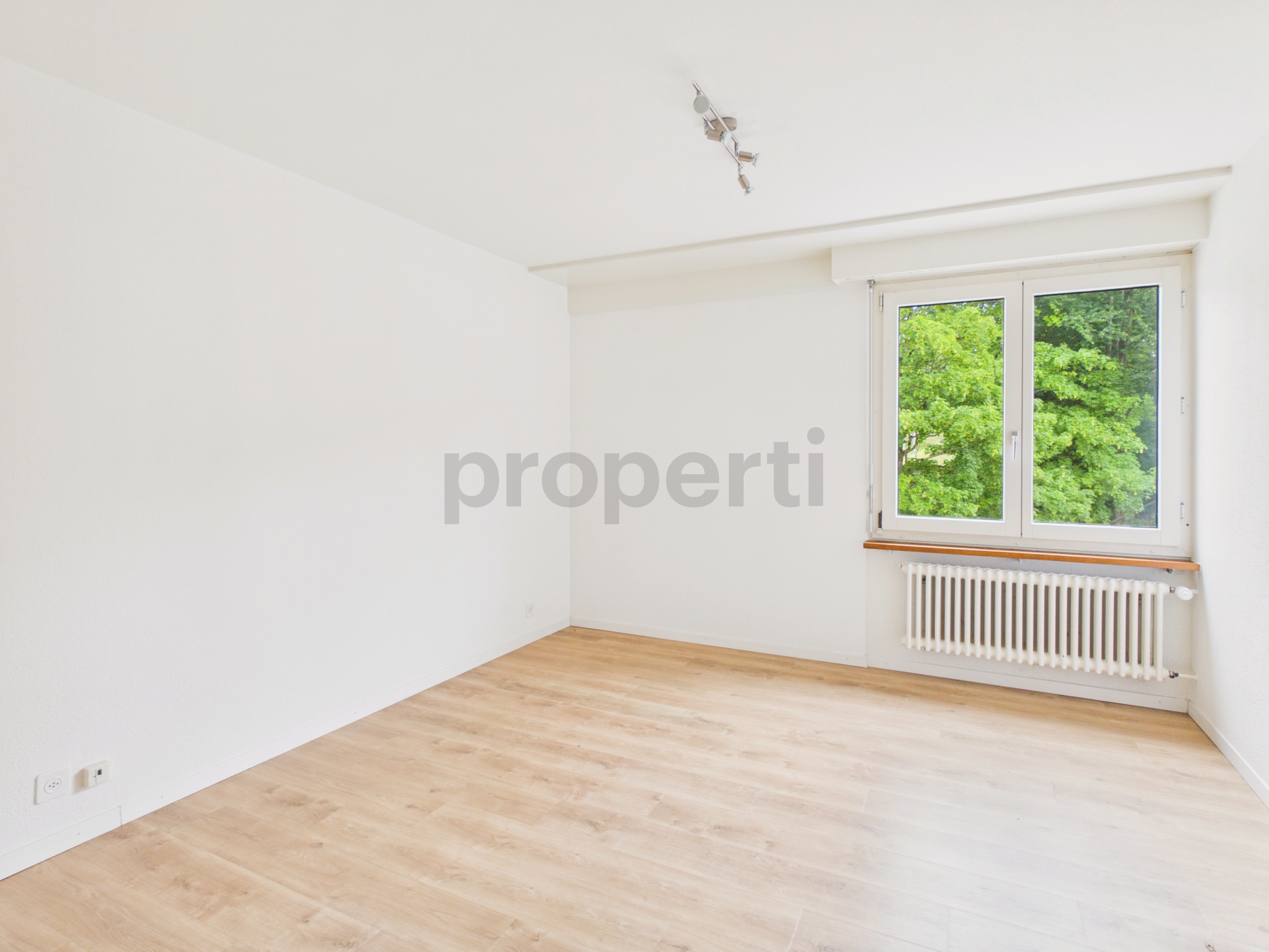 Helles, leeres Zimmer mit Fenster und Heizkörper