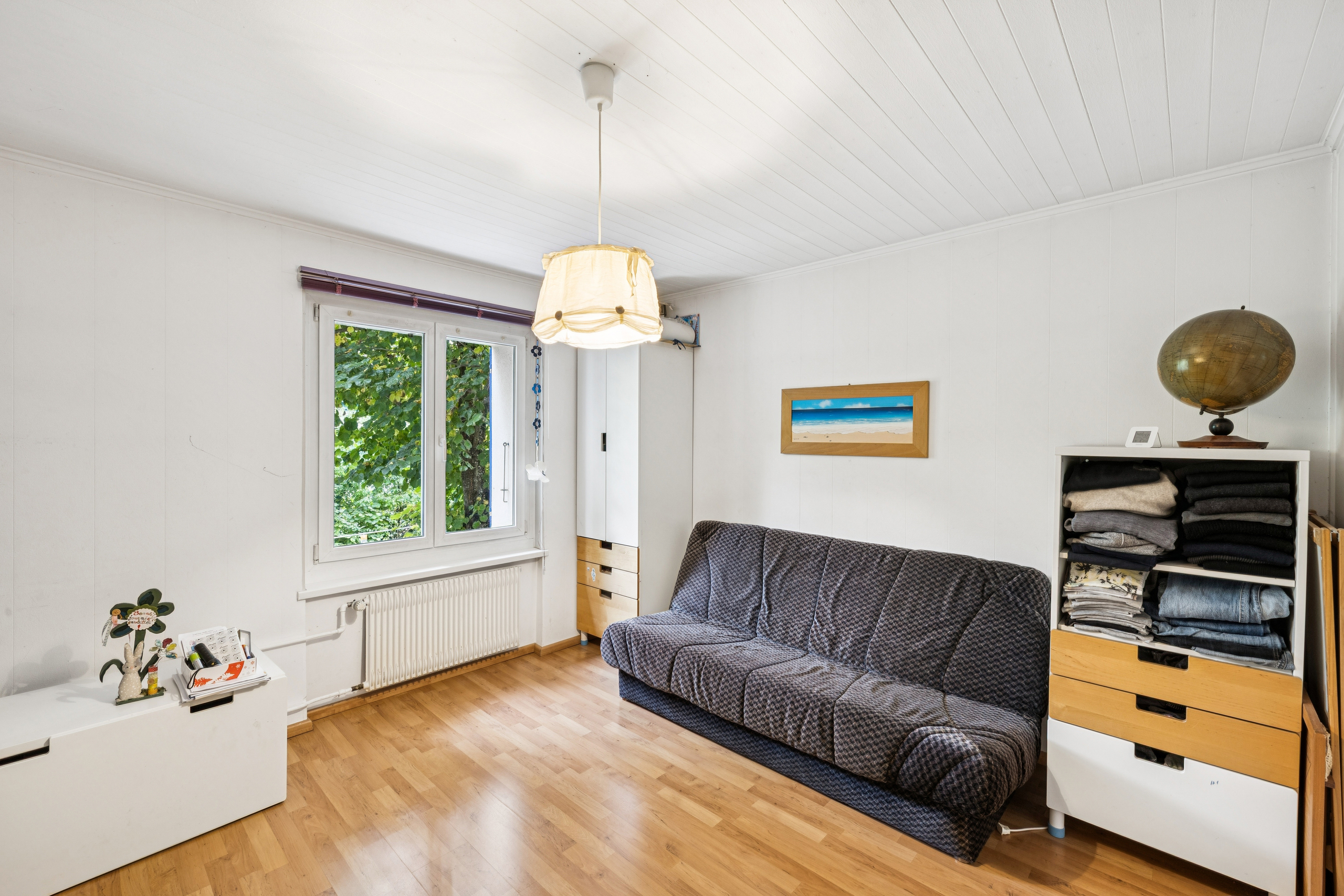 Helles, schlichtes Wohn-/Arbeitszimmer mit Sofa und Fenster