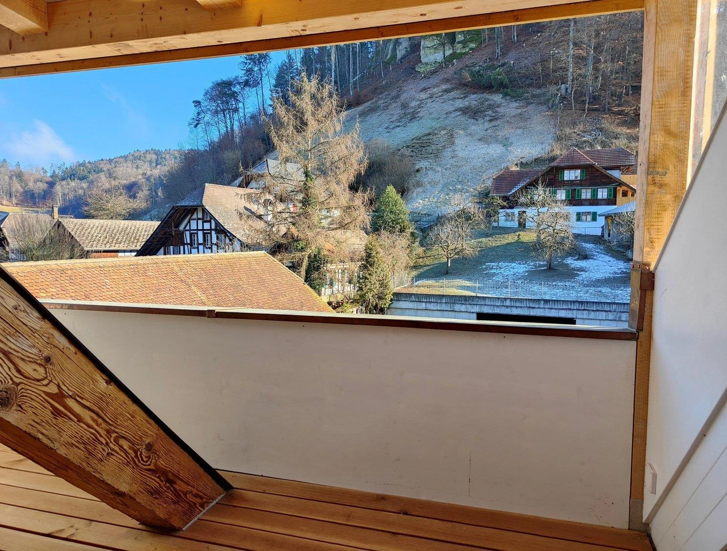 Blick von einem Holzbalkon auf ein ländliches Tal