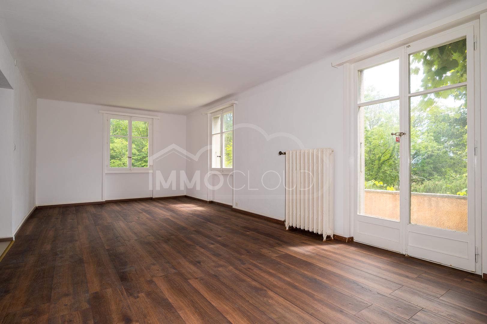 Leerer heller Raum mit Holzboden und Gartenblick