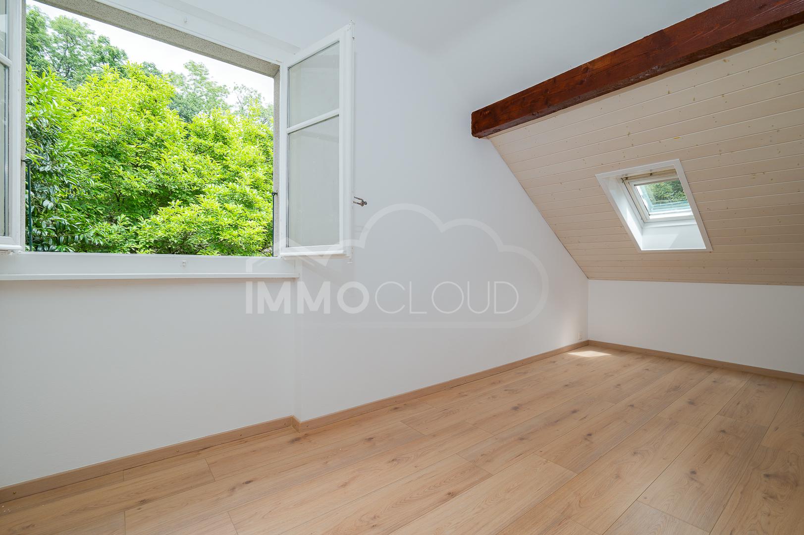 Helles Dachzimmer mit offenem Fenster und Blick ins Grüne