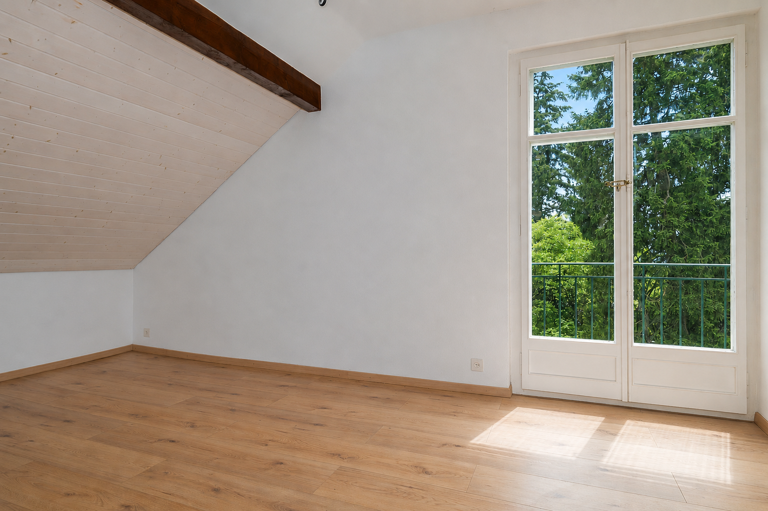 Helles, leerstehendes Dachgeschosszimmer mit Balkonfenstertür