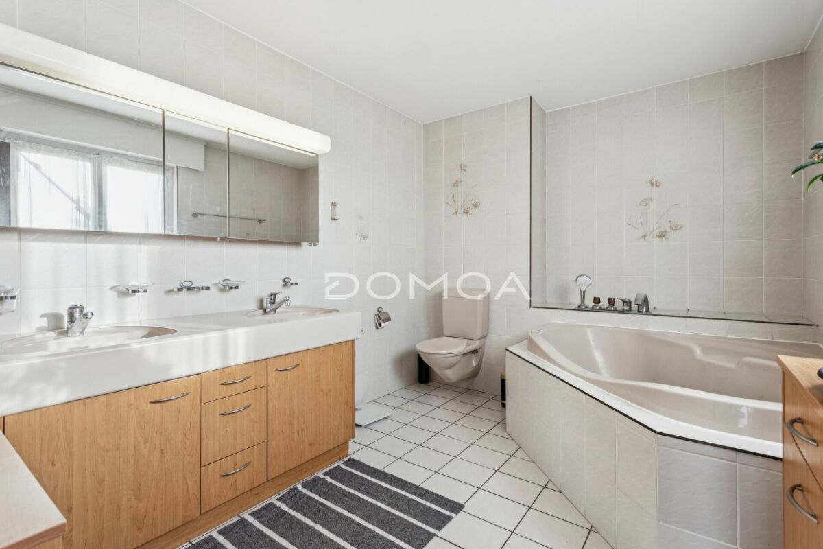 Helles Badezimmer mit Doppelwaschtisch und Eckbadewanne