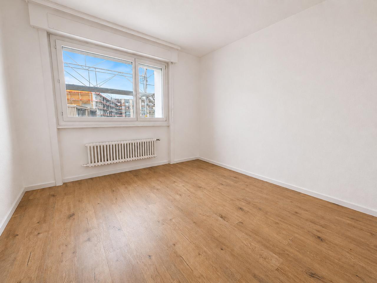 Leerer, heller Raum mit Holzoptikboden und Fenster