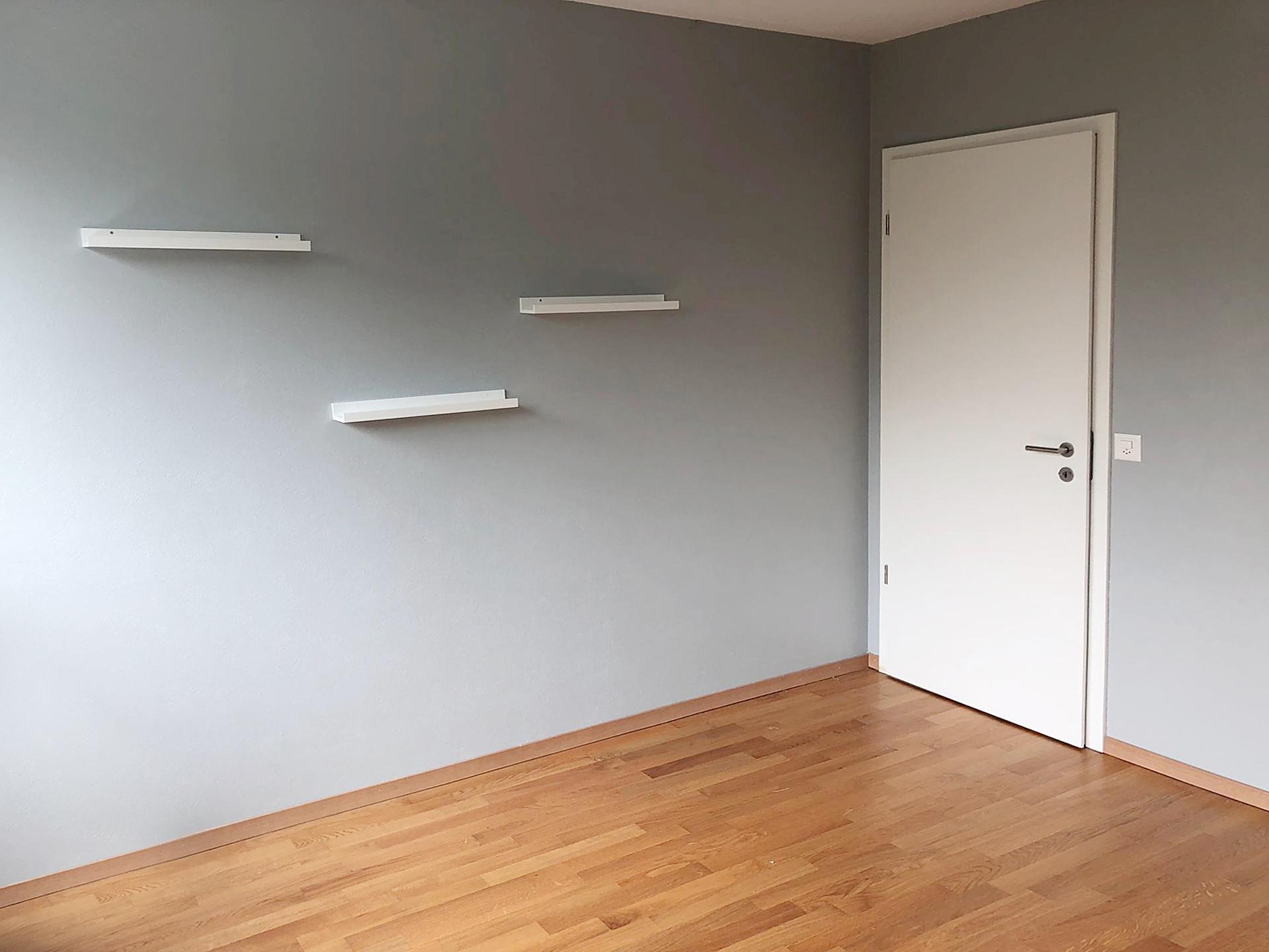 Leerer Raum mit grauer Wand und Parkettboden