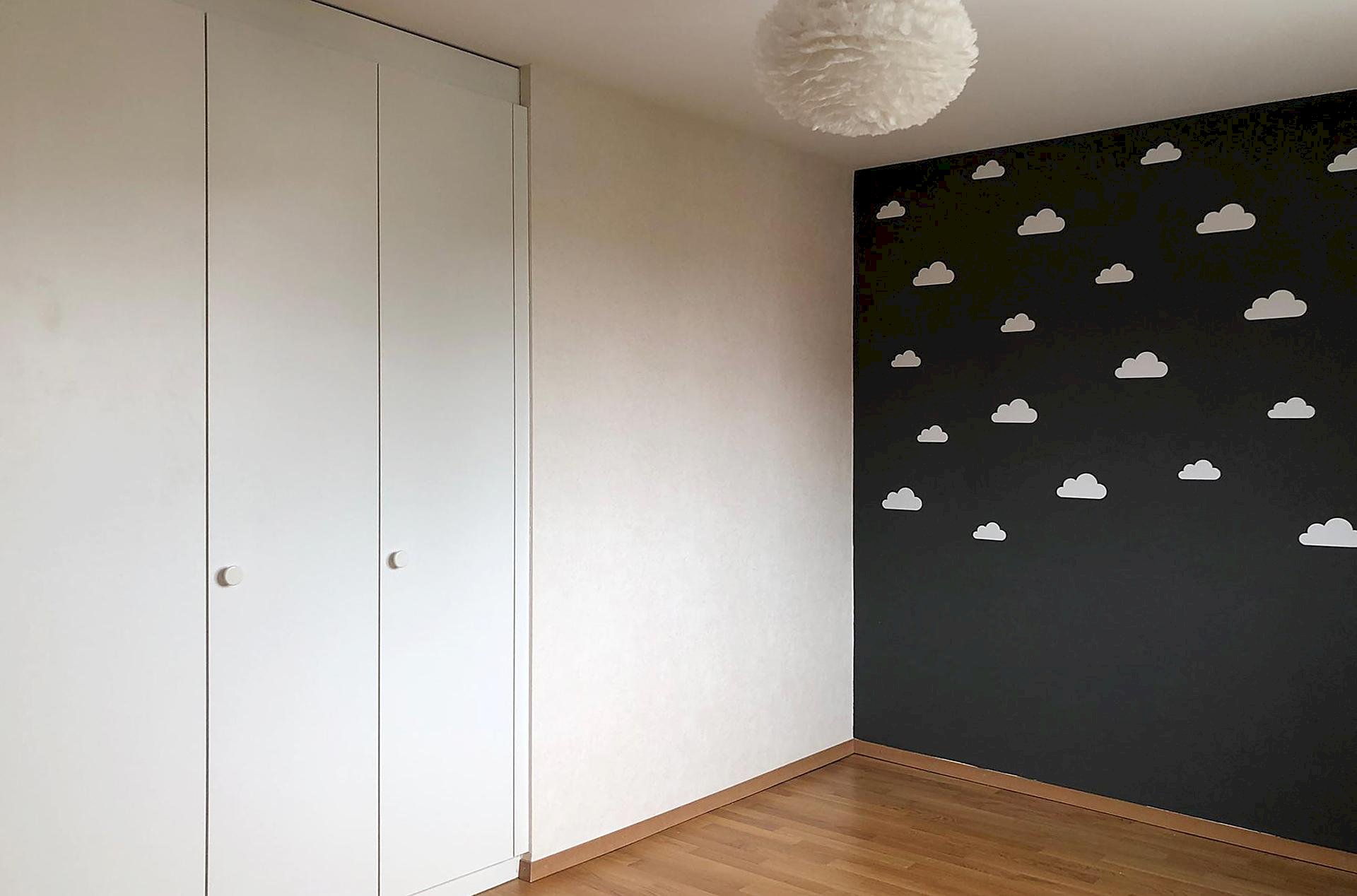 Kinderzimmer mit weißem Einbauschrank und Wolkentapete
