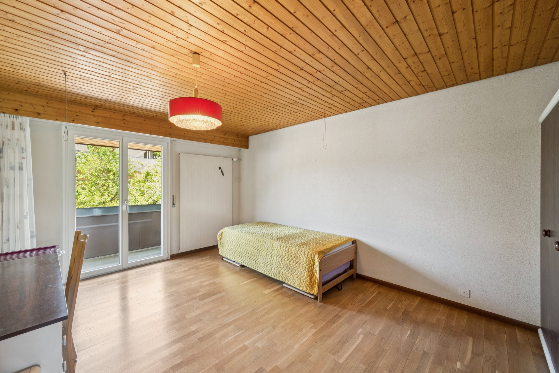 Helles Schlafzimmer mit Holzdecke und Balkonzugang