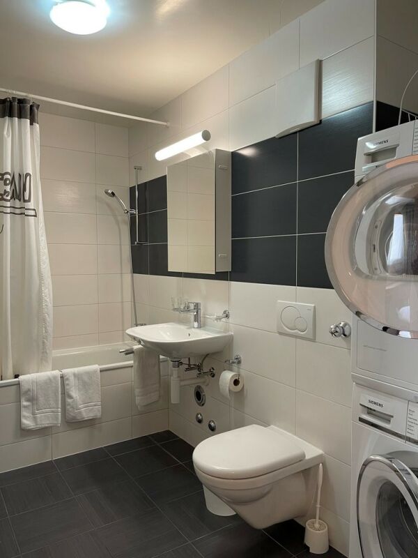 Badezimmer mit Badewanne, Waschbecken und Wand-WC