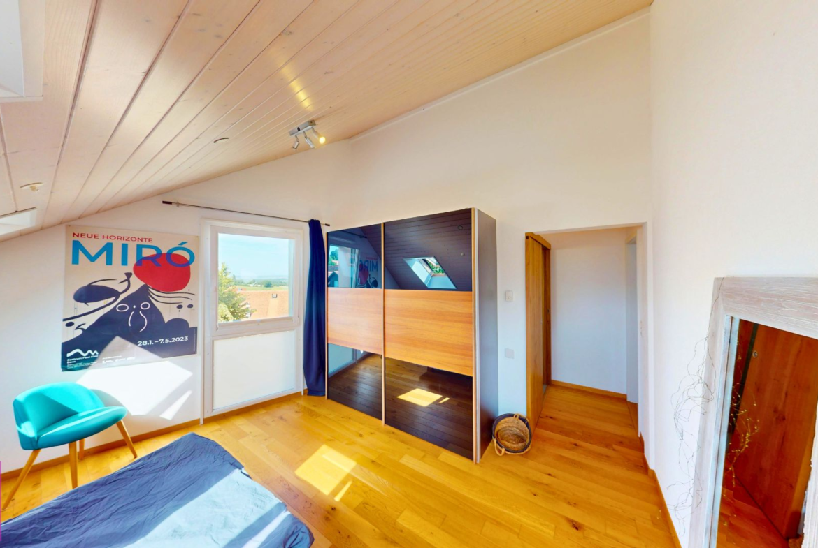 Helles Dachzimmer mit Bett, Schrank und Kunstposter