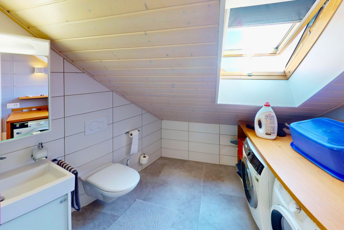 Helles Dachgeschoss-Badezimmer mit Hauswirtschaftsecke