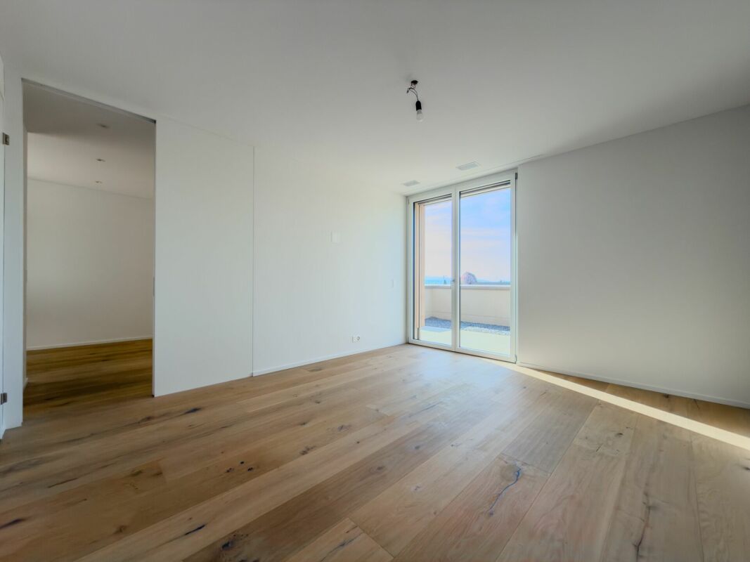 Heller leerer Raum mit Holzboden und Balkonzugang
