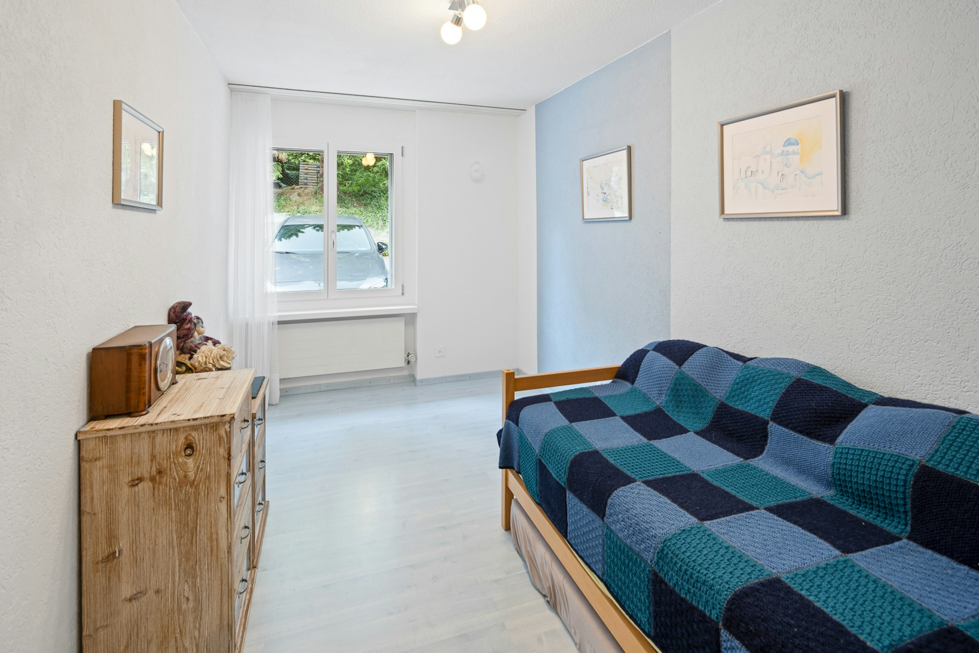 Helles Schlafzimmer mit Einzelbett und Fensterblick ins Grüne