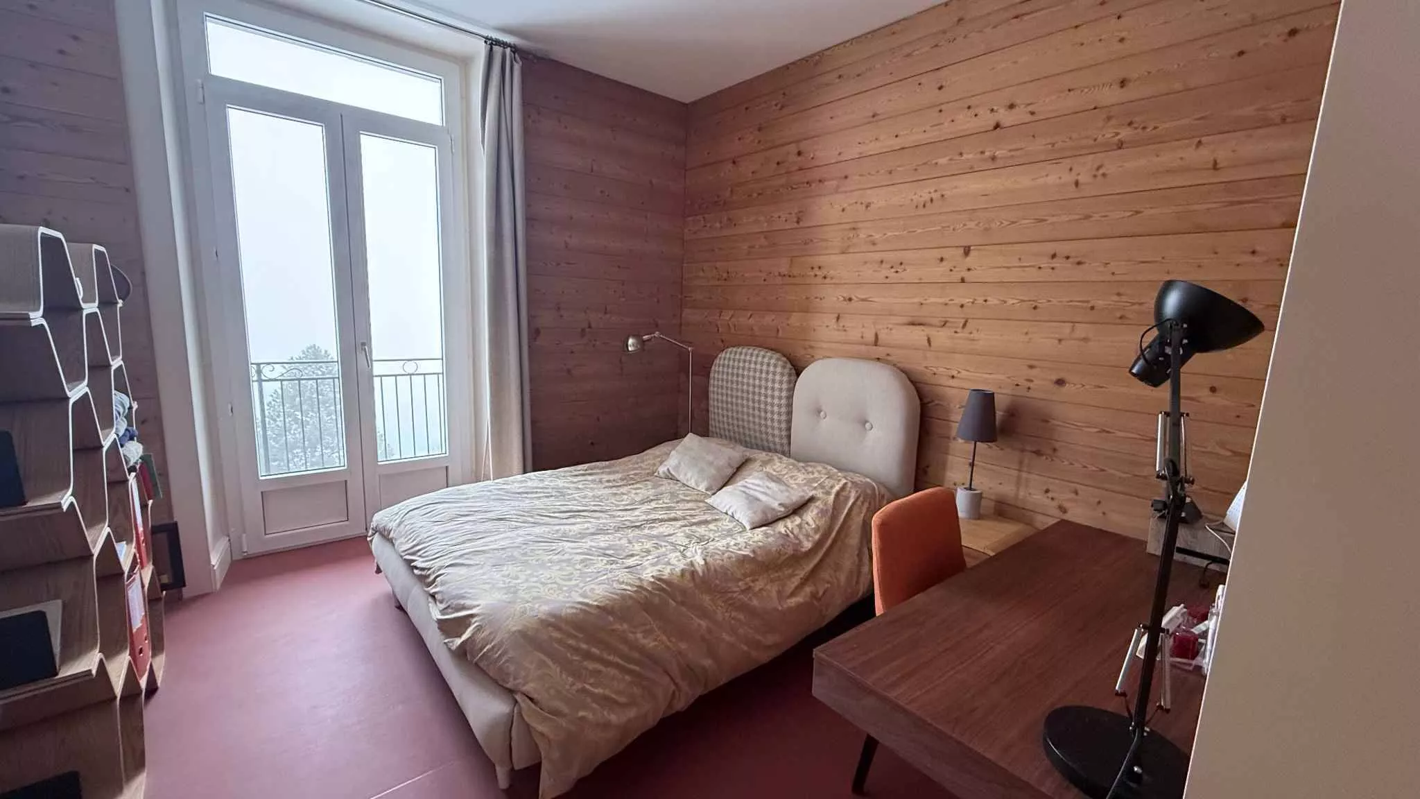 Helles Schlafzimmer mit Holzwänden und Balkonzugang