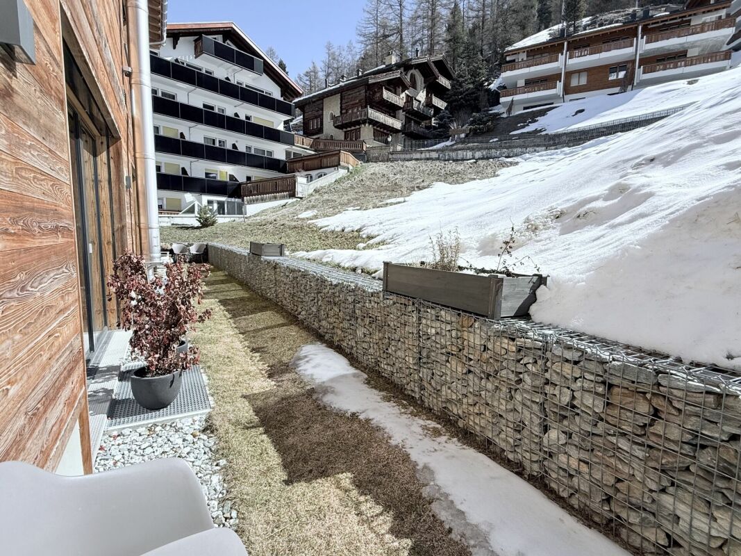 Außenansicht eines alpinen Wohnhauses mit verschneitem Hang