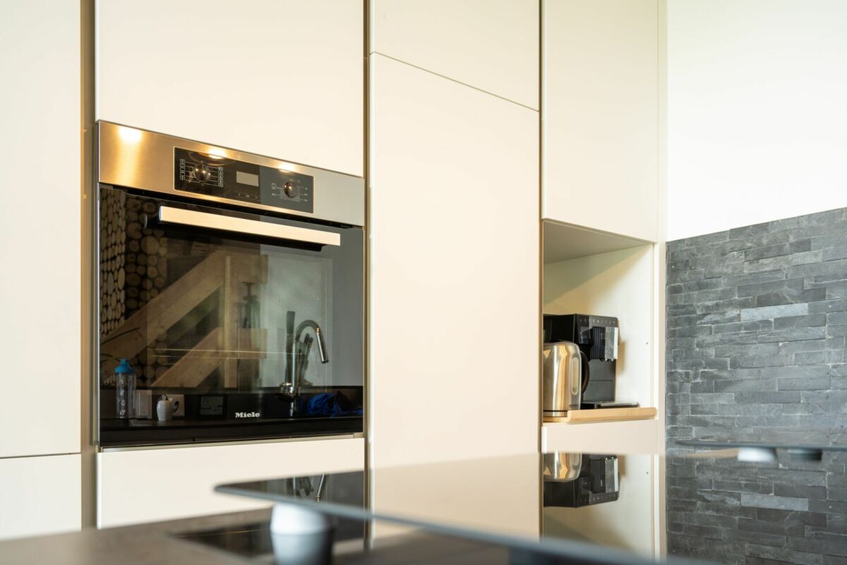 Moderne Küche mit Hochschrank und Natursteinwand