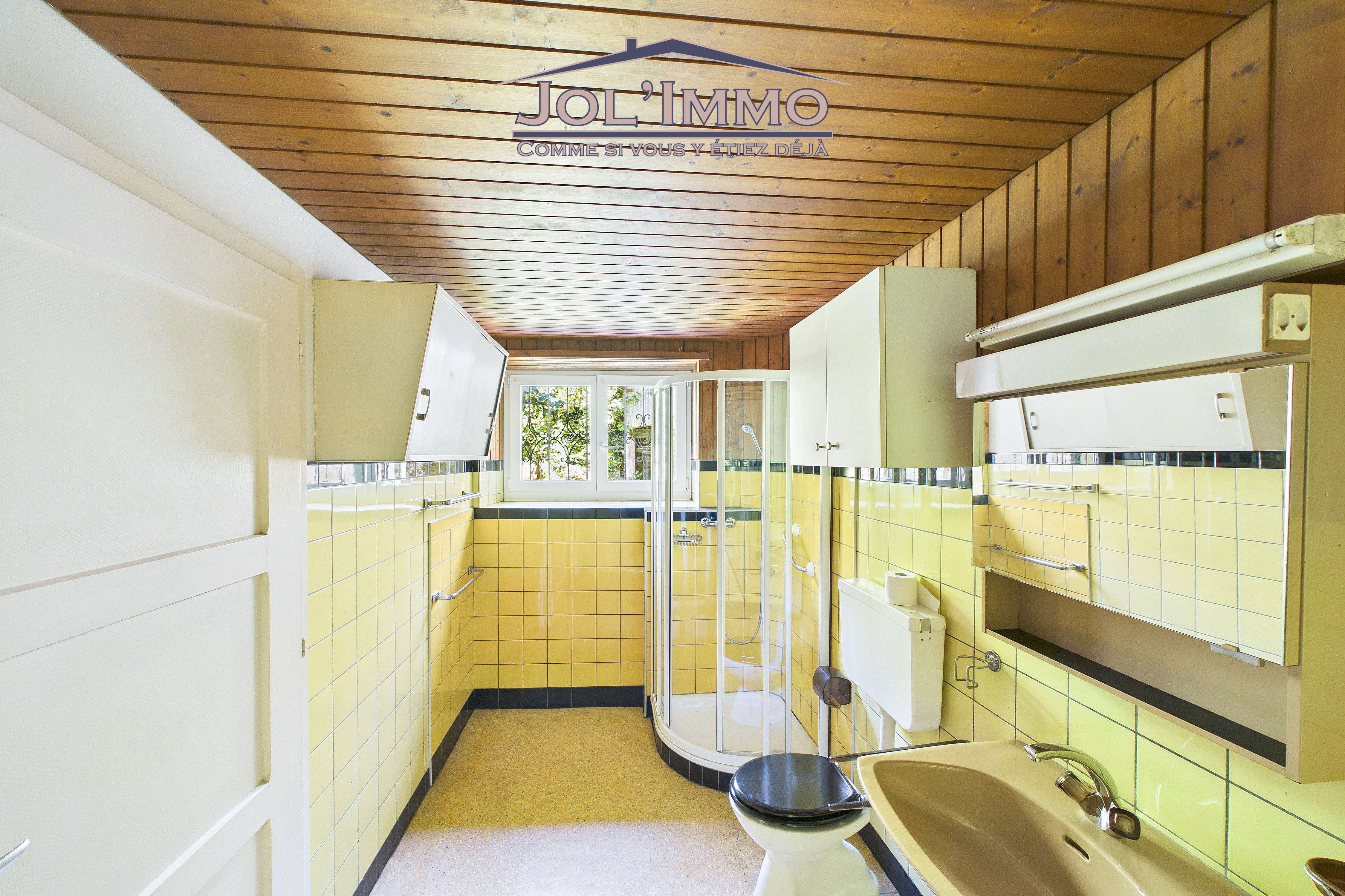 Badezimmer mit gelb gefliesten Wänden und Holzdecke