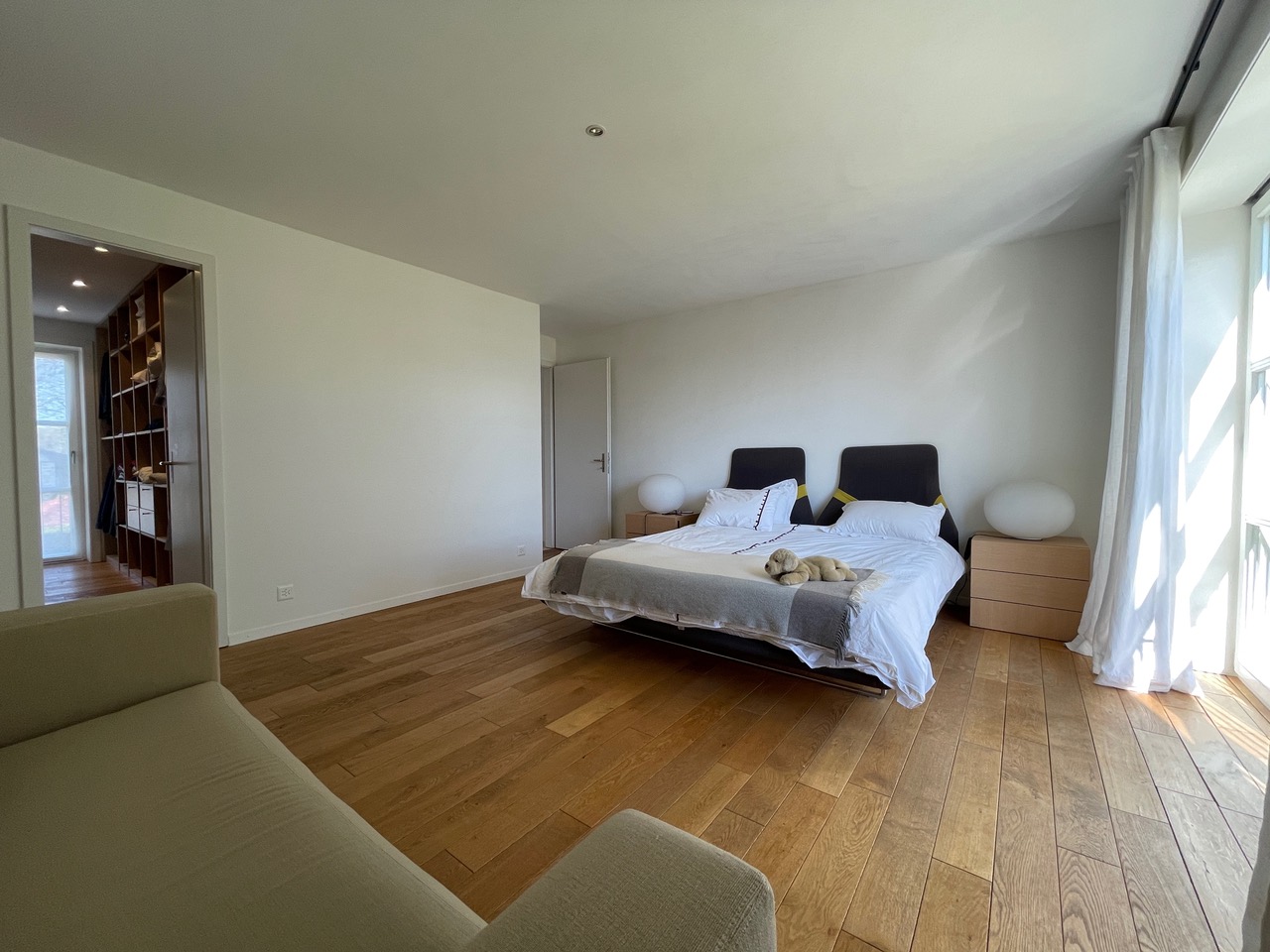 Helles Schlafzimmer mit Holzboden und großem Fenster
