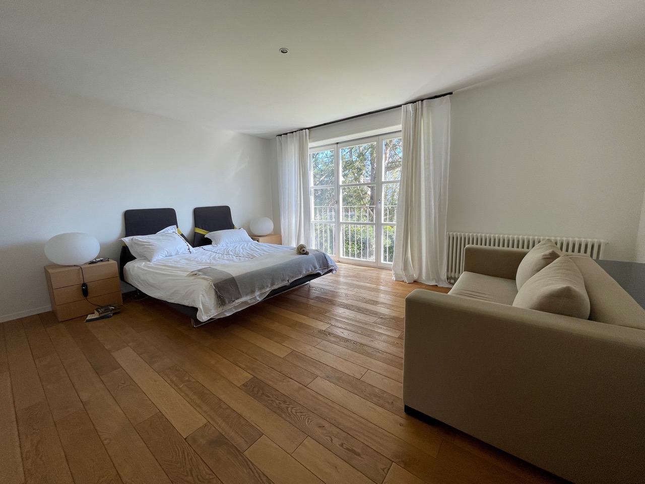 Schlafzimmer mit Balkonfenster und Holzparkett