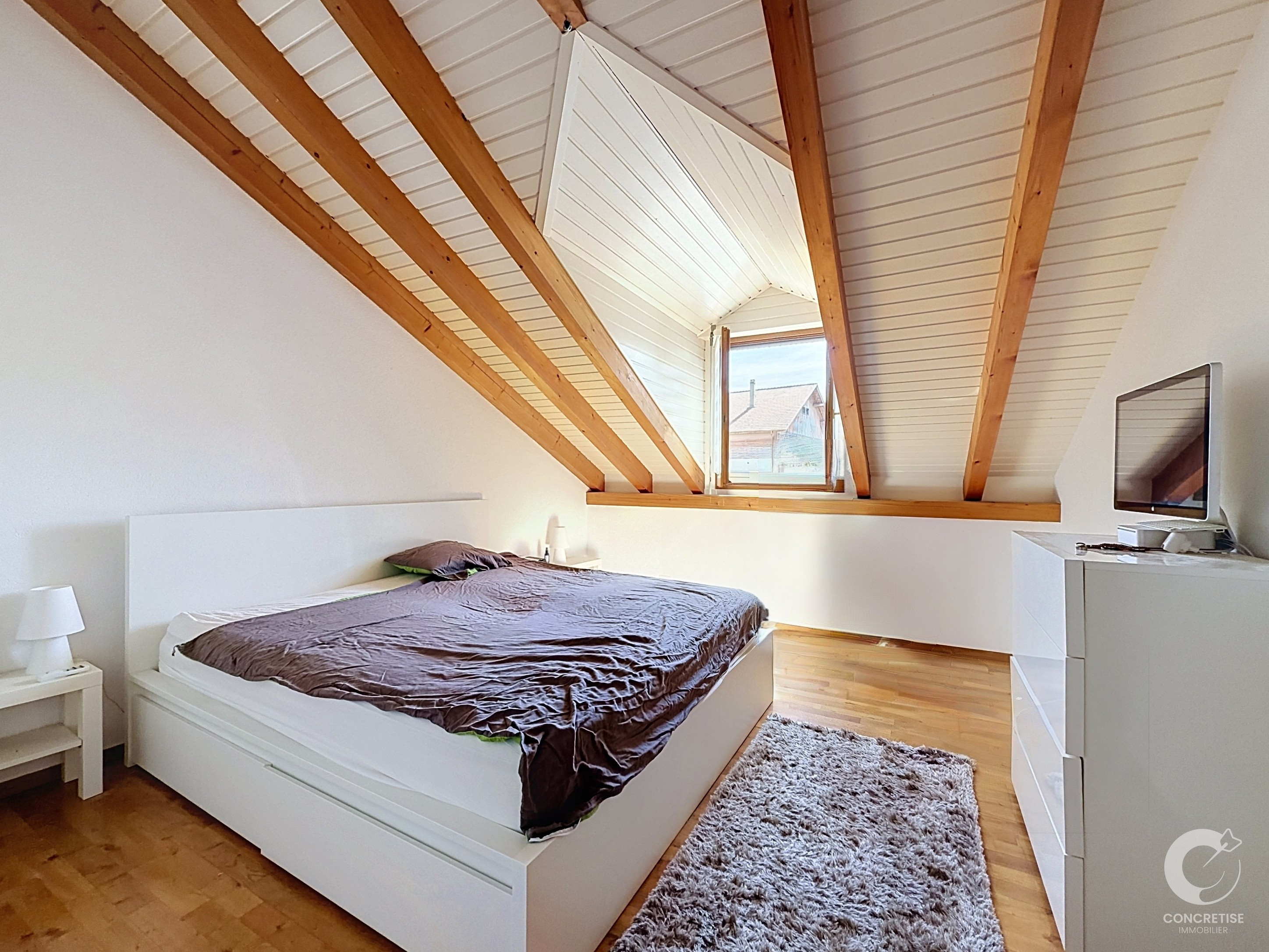 Dachgeschoss-Schlafzimmer mit sichtbaren Holzbalken