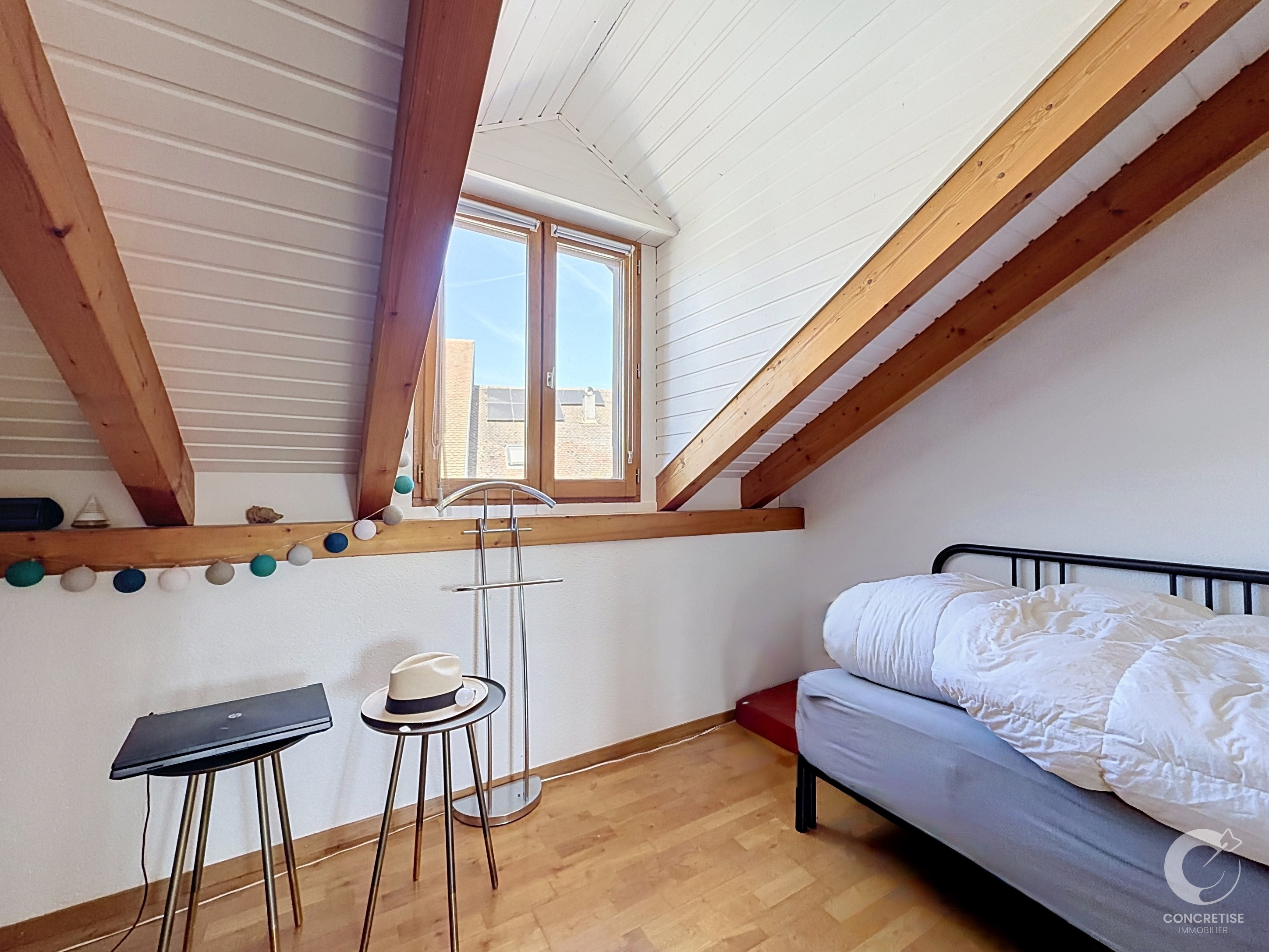 Dachzimmer mit Bett und Fenster