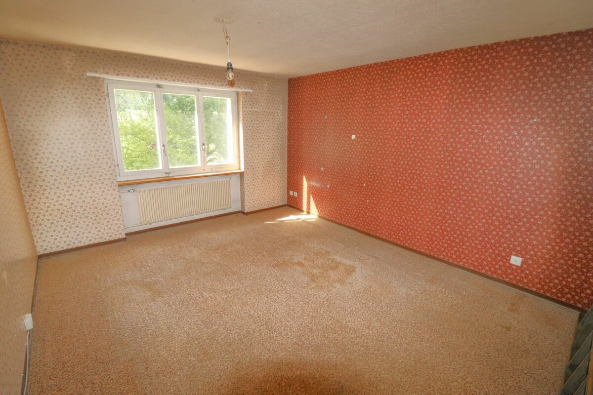 Leeres Schlafzimmer mit Teppich und gemusterten Tapeten