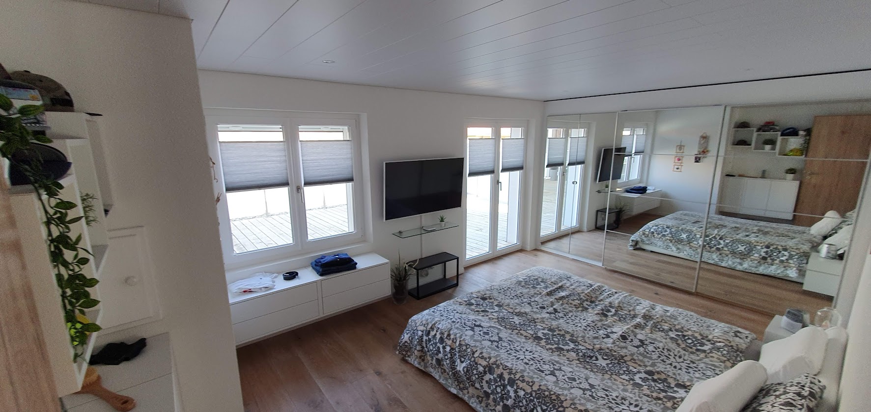 Helles Schlafzimmer mit Spiegelfront und Balkonzugang