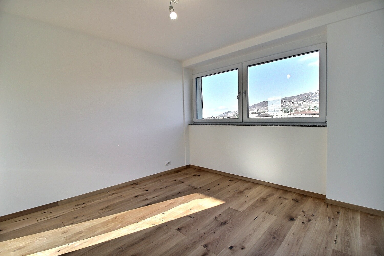 Heller leerer Raum mit Holzfußboden und Fensterblick
