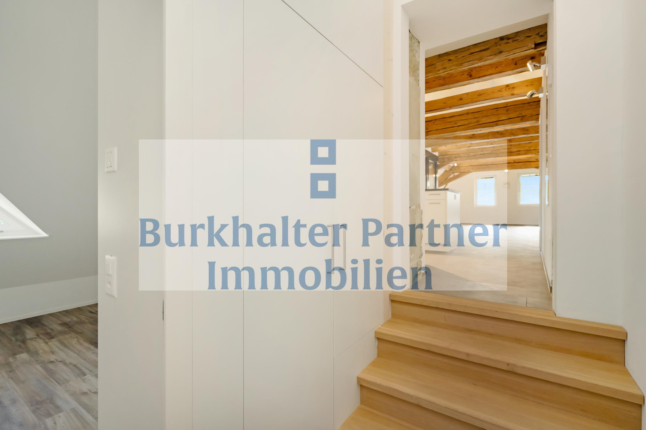 Helle Dachgeschoss-Treppe mit sichtbaren Holzbalken