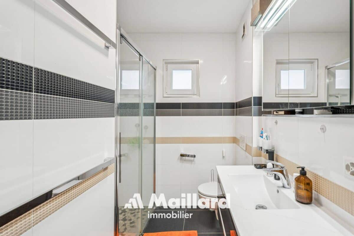 Modernes Badezimmer mit Glasdusche und Spiegelwaschtisch